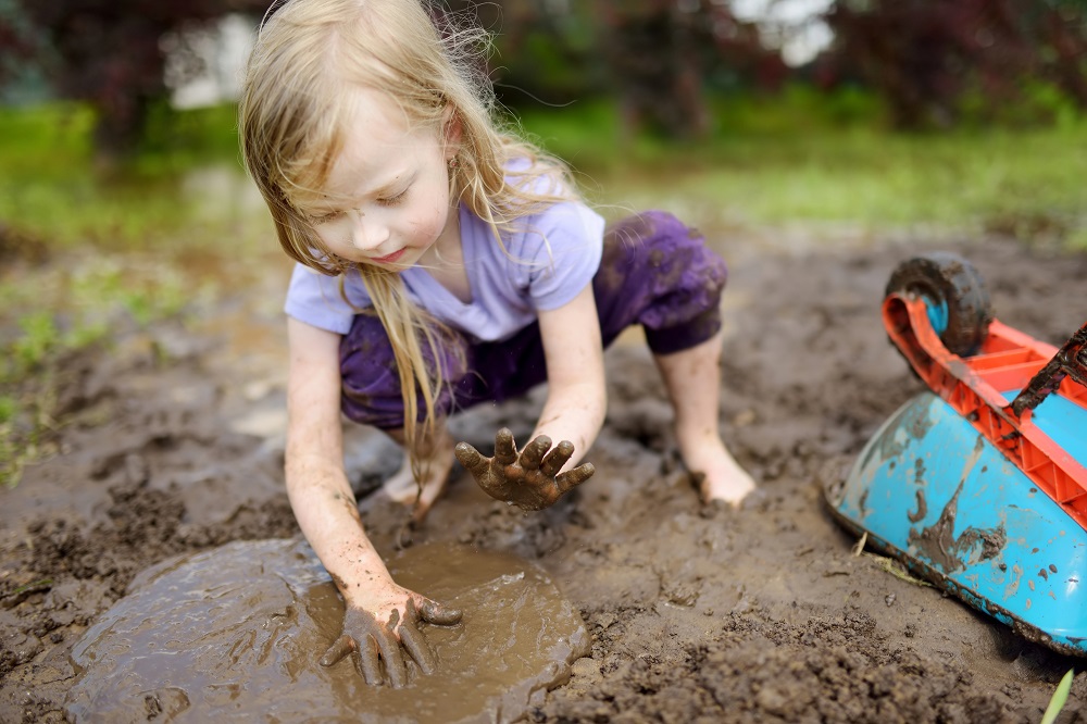девочка играет в грязи