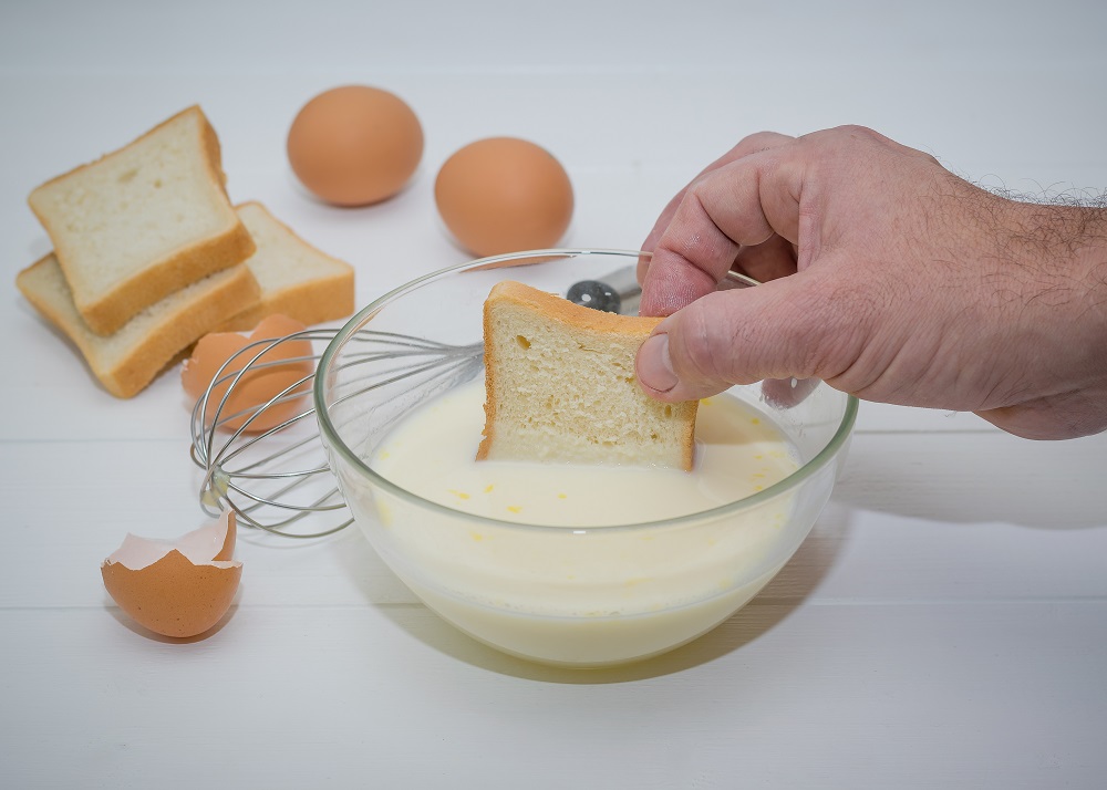 мужчина макает хлеб в молоко